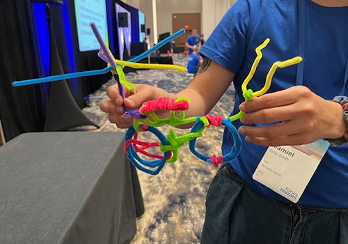 man holding a bicycle made from pipe cleaners made during a team building activity