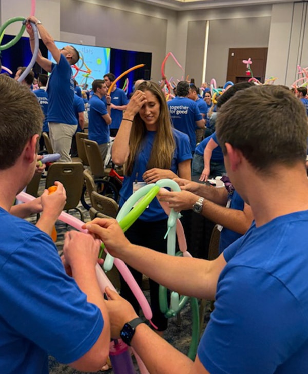 Group of people making large balloon hats as an activity within the wheels for the world team building program